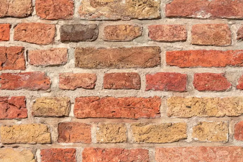 Detailed image of a rough, multicolored brick wall texture for backgrounds or design.